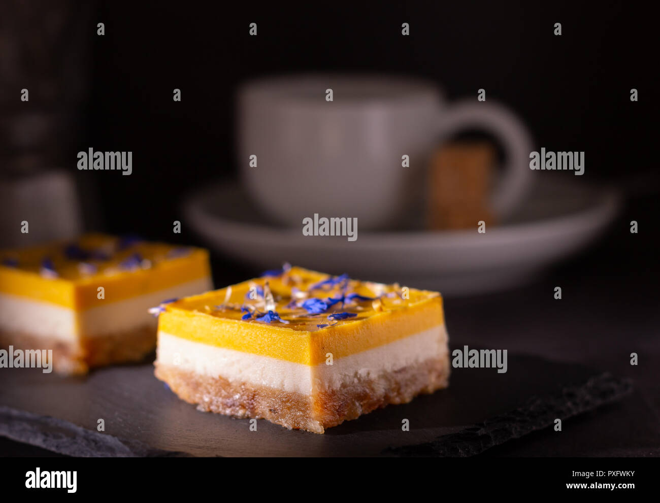 Hausgemachte Kalk und Mango Kuchen auf einen schwarzen Stein Platte mit Kaffee Stockfoto