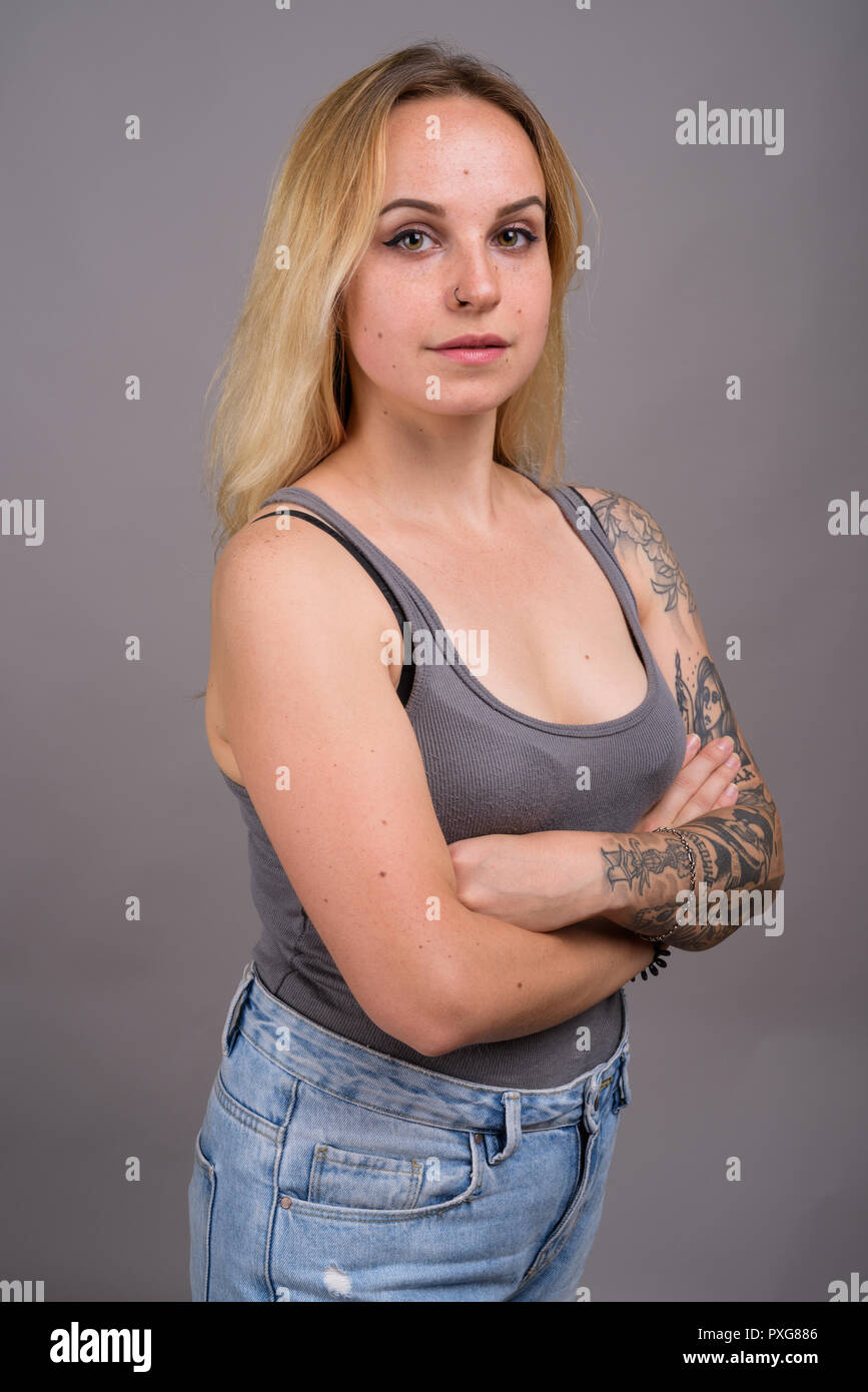 Junge schöne Frau mit blonden Haaren gegen grauer Hintergrund Stockfoto