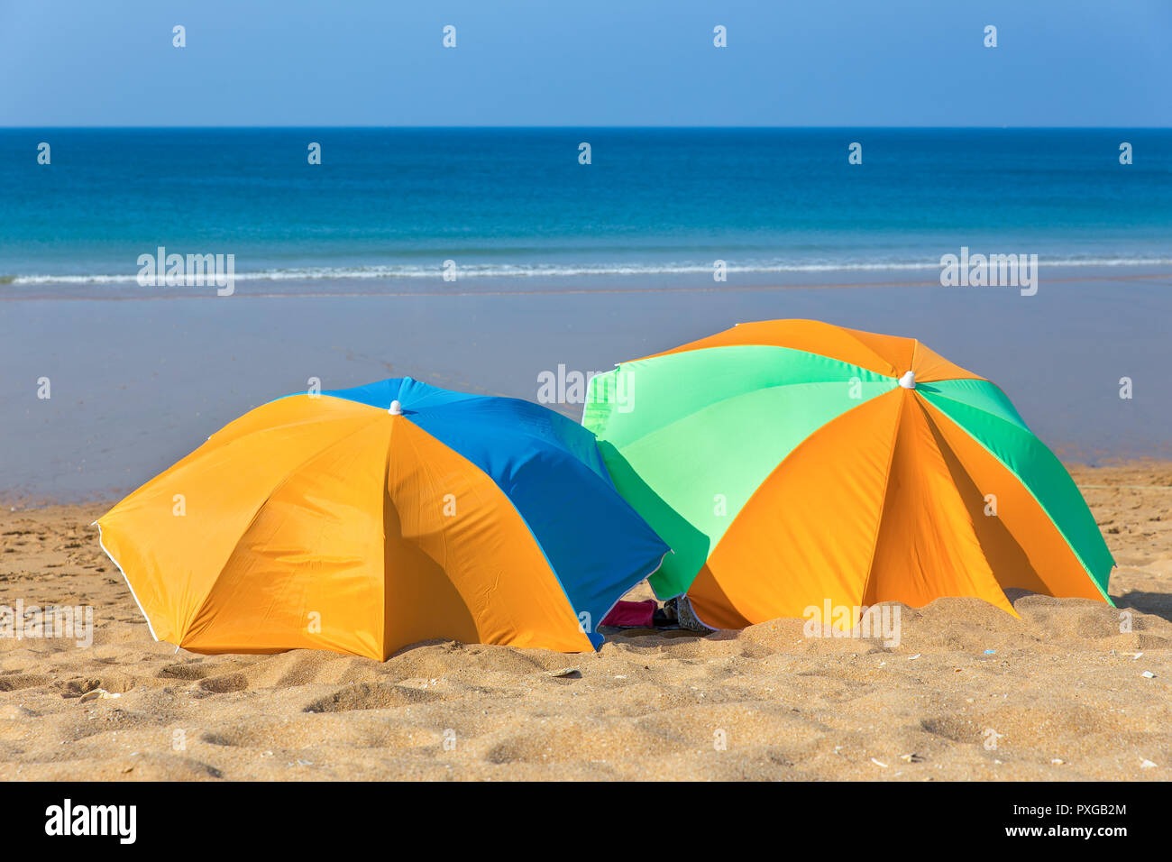 Zwei bunte Sonnenschirme am Strand am Meer Stockfoto Zwei bunte Sonnenschirme am Strand am Meer Stockfoto