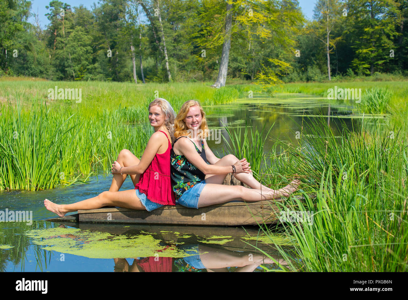 Zwei jungen kaukasischen Frauen an der Stream in der Natur sitzen Stockfoto