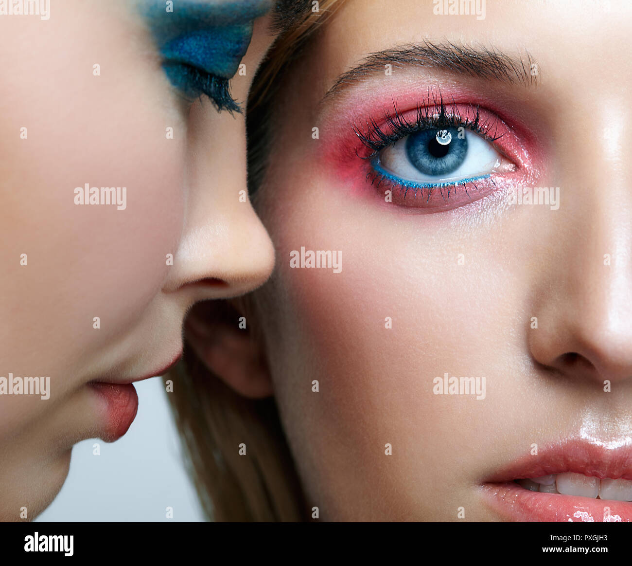 Zwei junge Frauen mit Blau und Rosa smoky euen glitter Make-up und glänzende Haut. Nahaufnahme der Blonde und brünette Mädchen. Weibliche Freundschaft Konzept. Stockfoto
