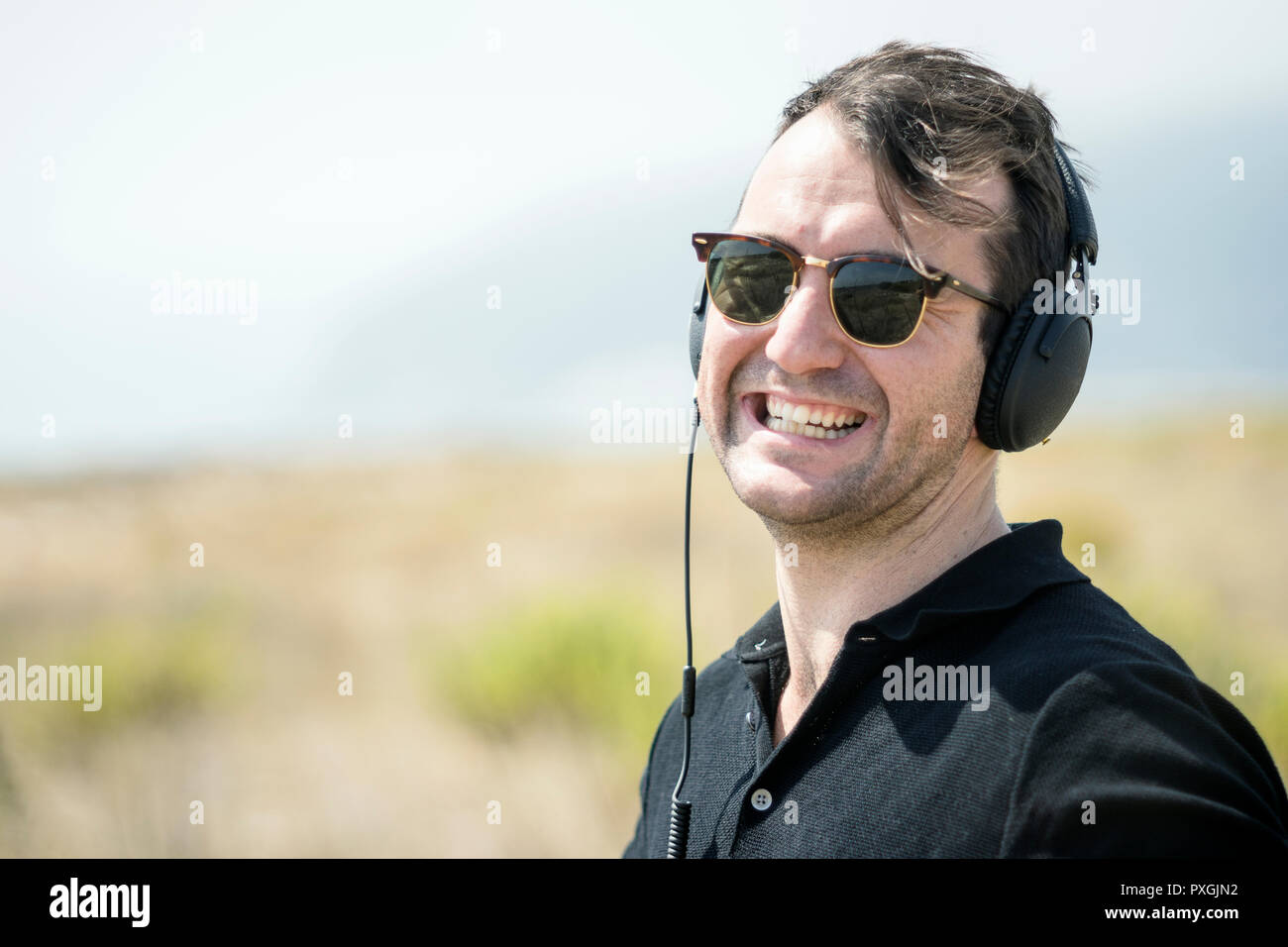 Jungen attraktiven Mann mit Sonnenbrille genießen Sie Musik auf seinem Kopfhörer Stockfoto