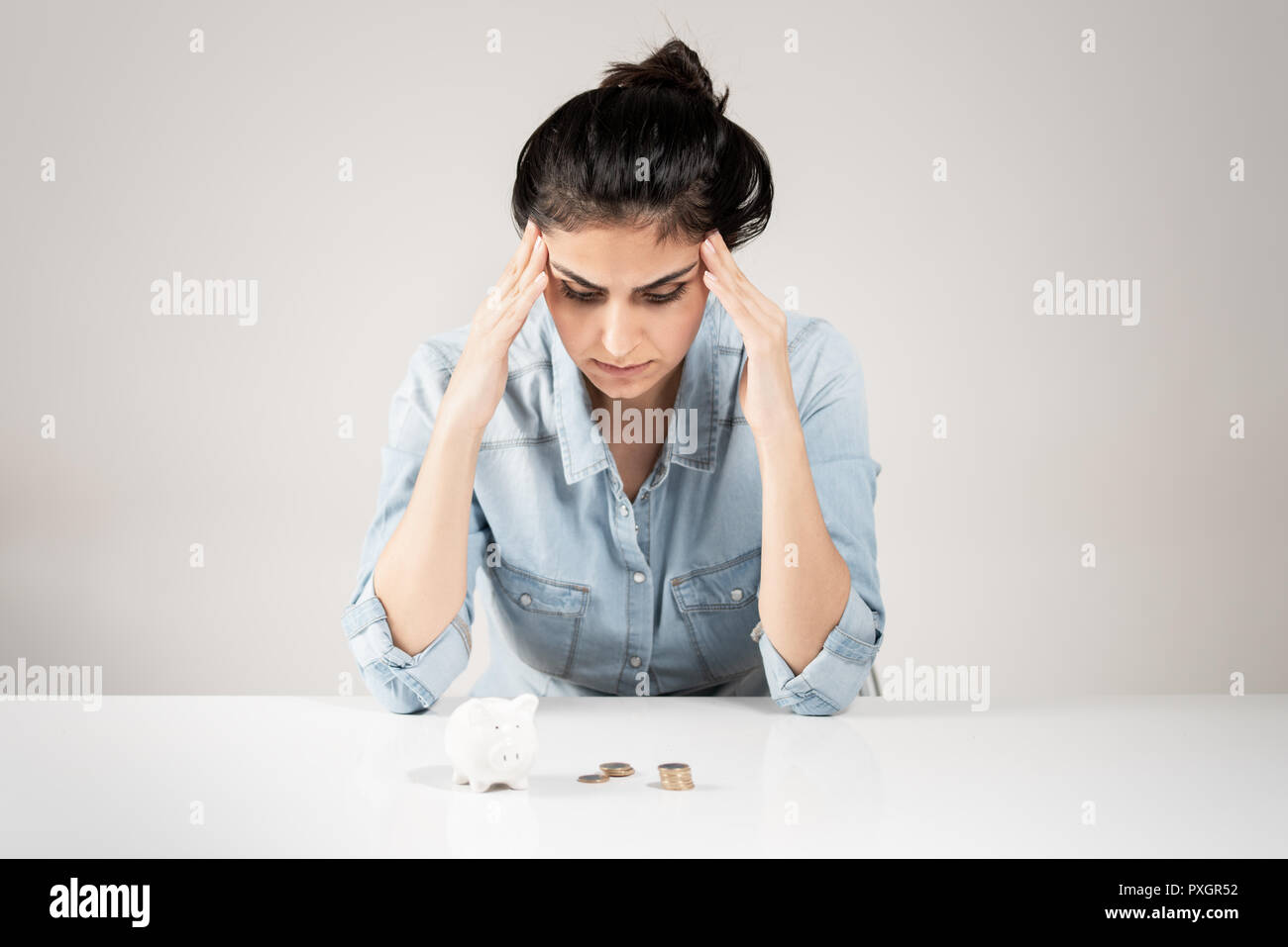 Junge Frau auf der Suche piggy Bank betont mit der Hand auf dem Kopf Stockfoto