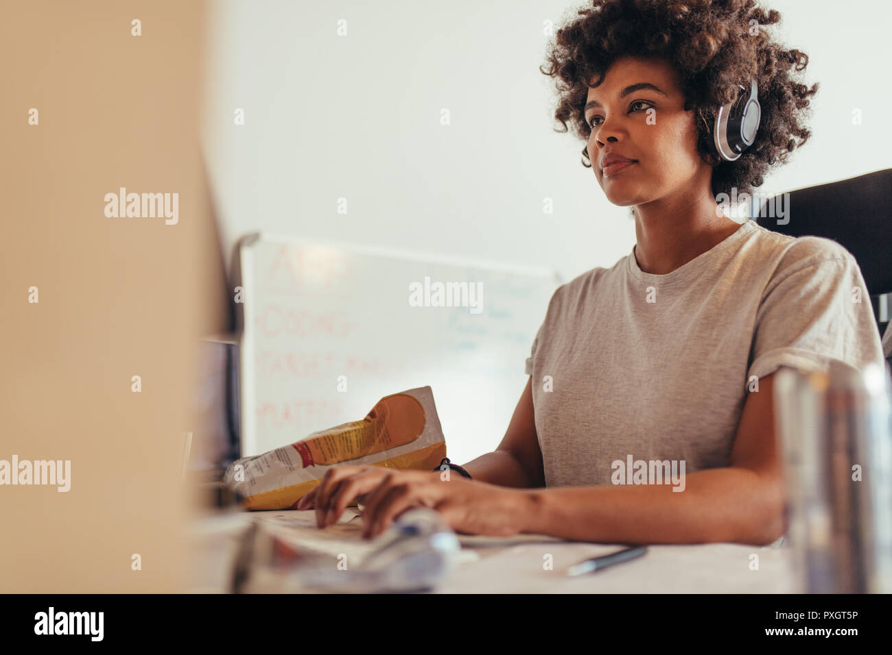 Programmiererin Datentypisierung Codes, die am Projekt in Software Development Company. Afrikanische Frau Kopfhörer tragen während der Arbeit konzentrieren. Stockfoto