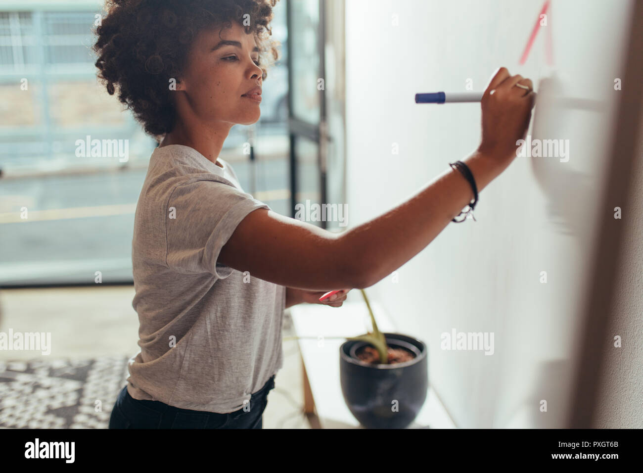 Junge afrikanische Geschäftsfrau ihre Ideen schreiben auf eine weiße Tafel im Büro. Frau schreiben Projektplan auf dem Whiteboard. Stockfoto