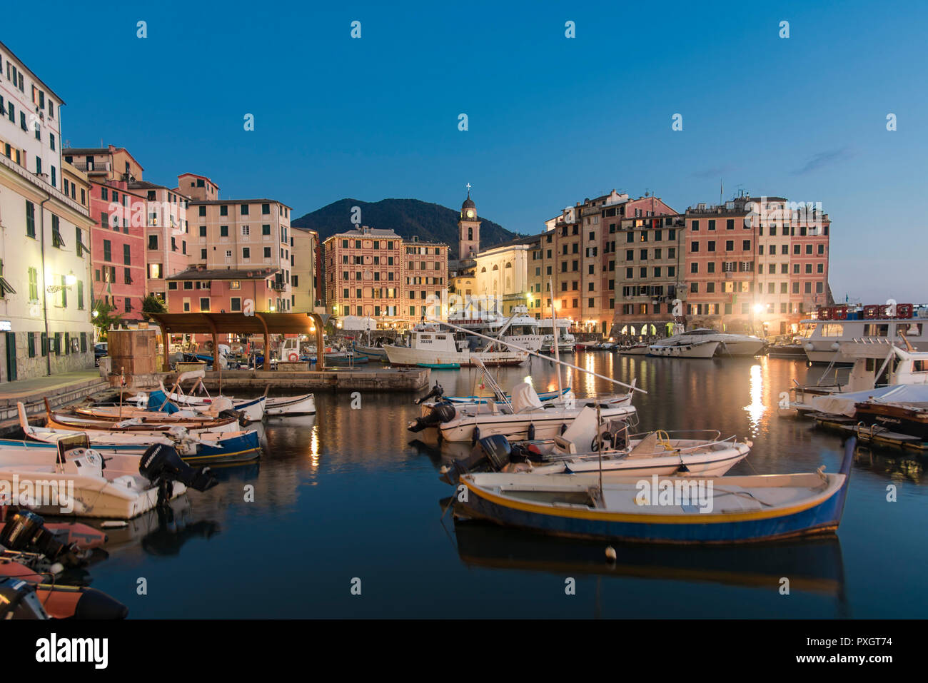 Ruhigen Hafen mit Fischerbooten, Rom, Italien im Abendlicht mit Reflexionen über die Lichter der traditionelle bunte waterfront Gebäude Stockfoto