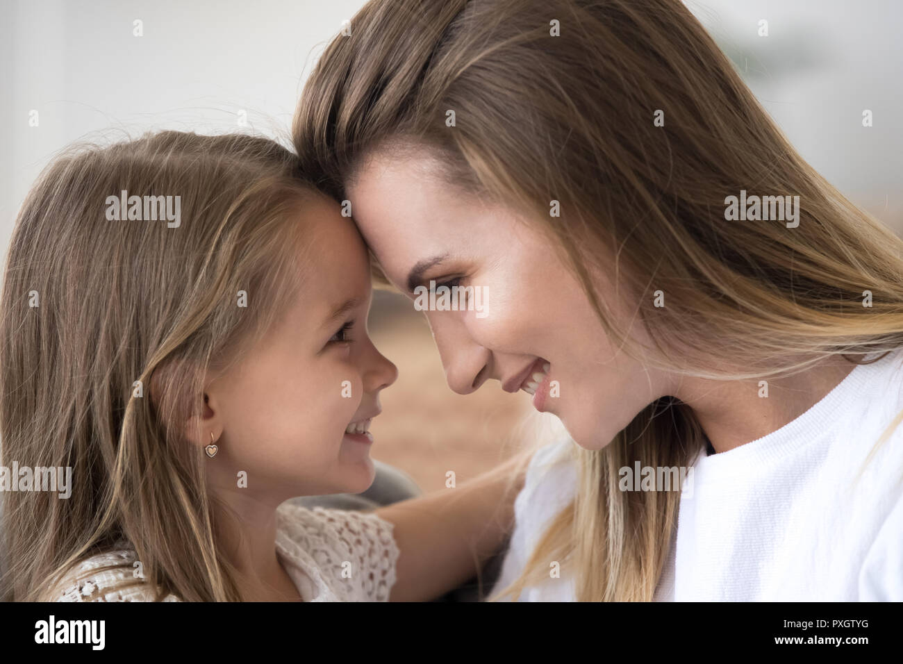 Liebevolle Mutter und Tochter schauen sie in die Augen der Stirn berühren. Stockfoto