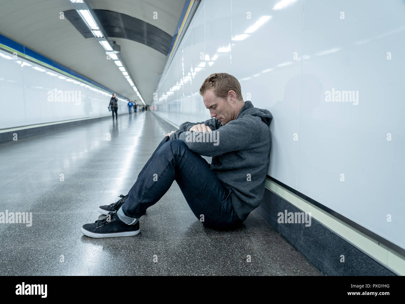 Miserable arbeitslose junge Mann weinen Drogensüchtigen Obdachlosen in Depression stress sitzen auf dem Boden Street U-Bahn Tunnel suchen verzweifelt lehnte sich an der Wand Stockfoto
