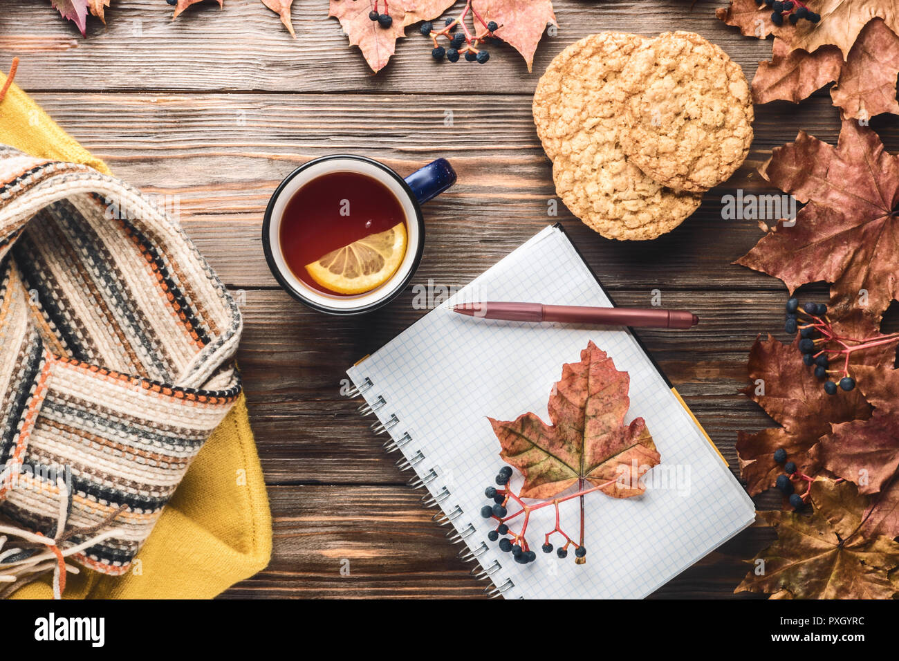 Herbst Mode saisonale Konzept gelb warm weicher Pullover skandinavischen Strickschal Tasse heißer schwarzer Tee Kaffee Fallen gefallen Ahornblätter auf hölzernen Tisch Stockfoto