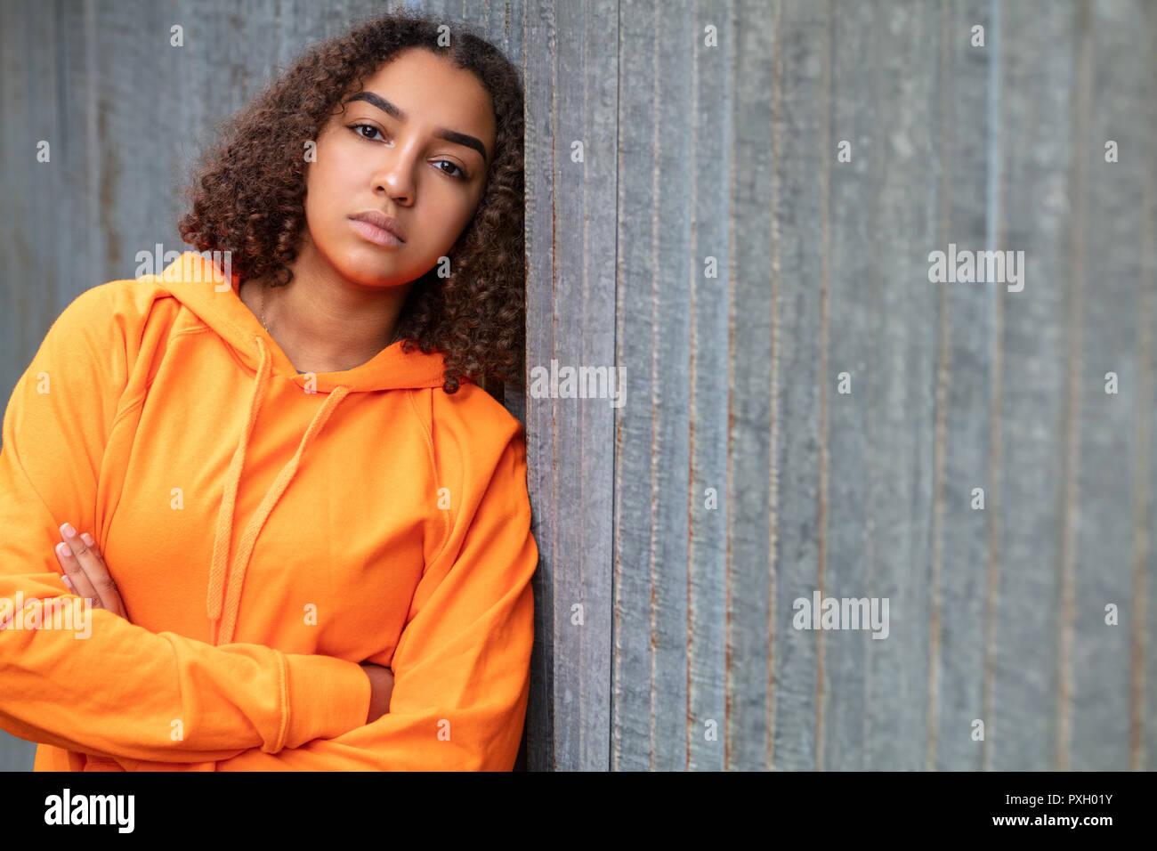 Schönen gemischten Rennen African American Girl Teenager weibliche junge Frau außerhalb tragen eine orange Hoodie traurig deprimiert oder nachdenklich Stockfoto