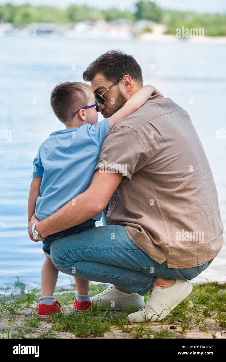 Vater und Sohn umarmen und berühren mit der Nase in der Nähe des Flusses im Park Stockfoto