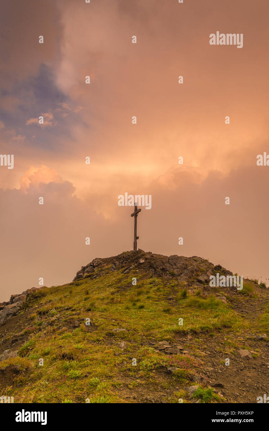 Kriegerdenkmal, Krieg, Kreuz, Kreuz, Gipfelkreuz auf einer Bergspitze in den italienischen Alpen mit einem klaren Himmel bei Sonnenuntergang im Hintergrund. Stockfoto