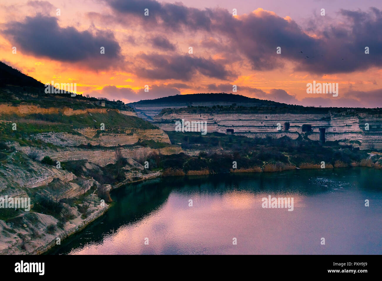 Einen verlassenen Steinbruch für die Entwicklung der weißen Kalkstein, lila Wolken am Himmel, die in der Oberfläche des Wassers Spiegeln, einem verlassenen Gebäude Stockfoto