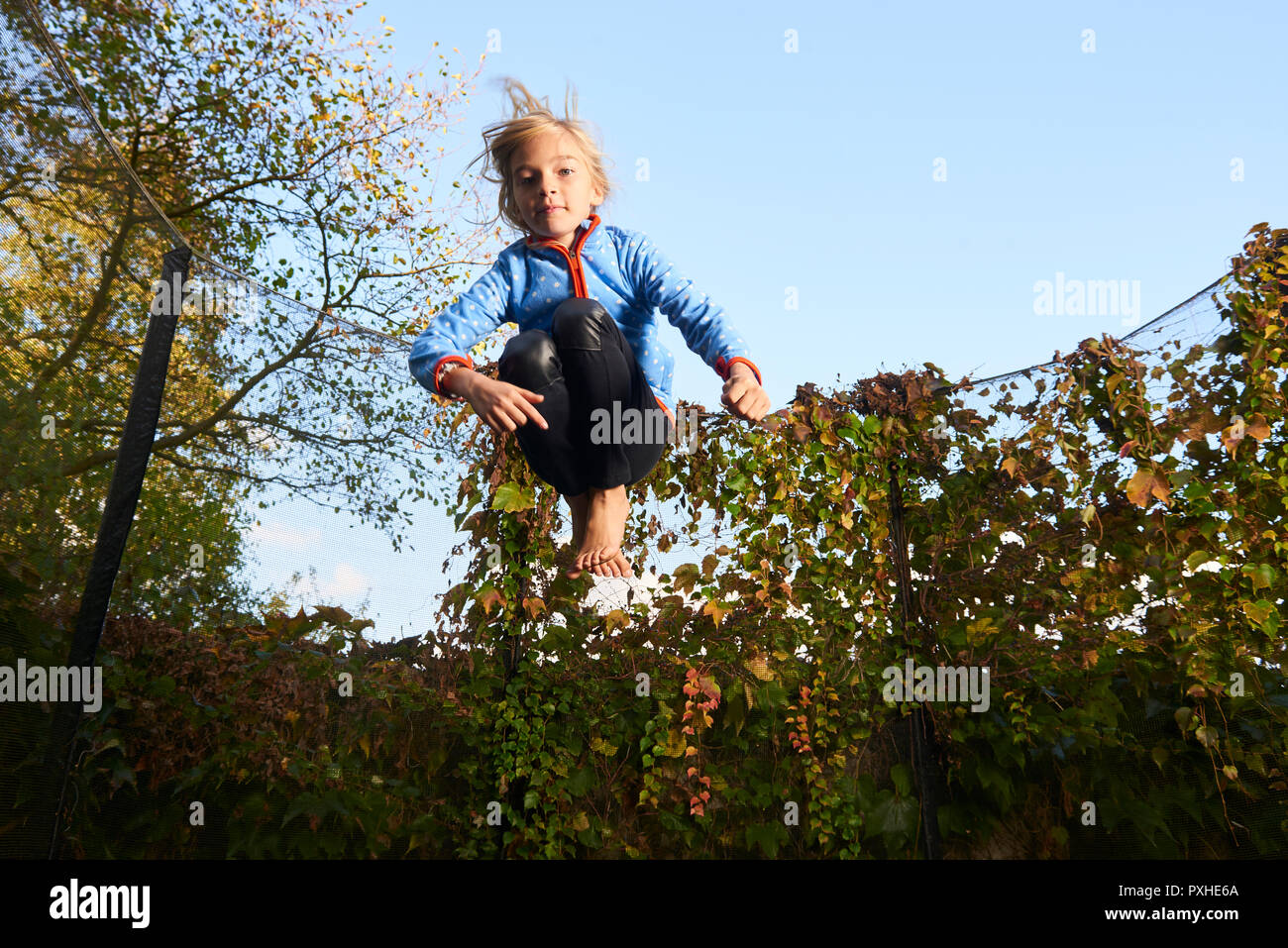 Kind niedlich blonde Mädchen spielen und springen auf Trampolin mit grünen Hintergrund Stockfoto