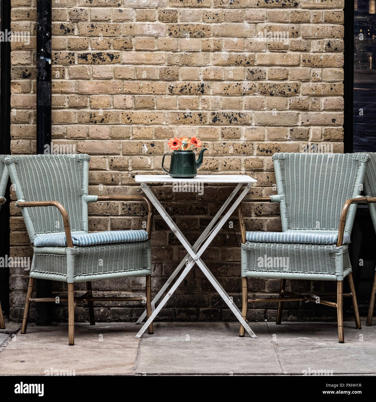 Tisch und zwei Stühle mit einem Teekanne voller Blumen außerhalb ein Cafe auf Clink Street, London, England Stockfoto