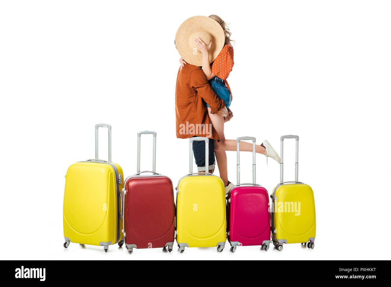 Verdeckt der jungvermählte Paar küssen hinter Stroh Hut mit arrangiert Koffer um auf Weiß isoliert Stockfoto