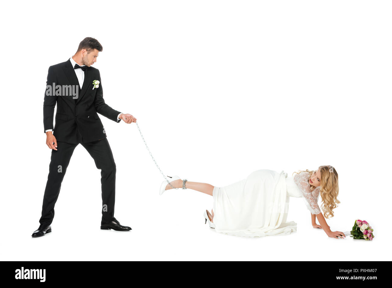 Hübscher Bräutigam holding Kette um Bräute Bein gebunden isoliert auf weißem Stockfoto