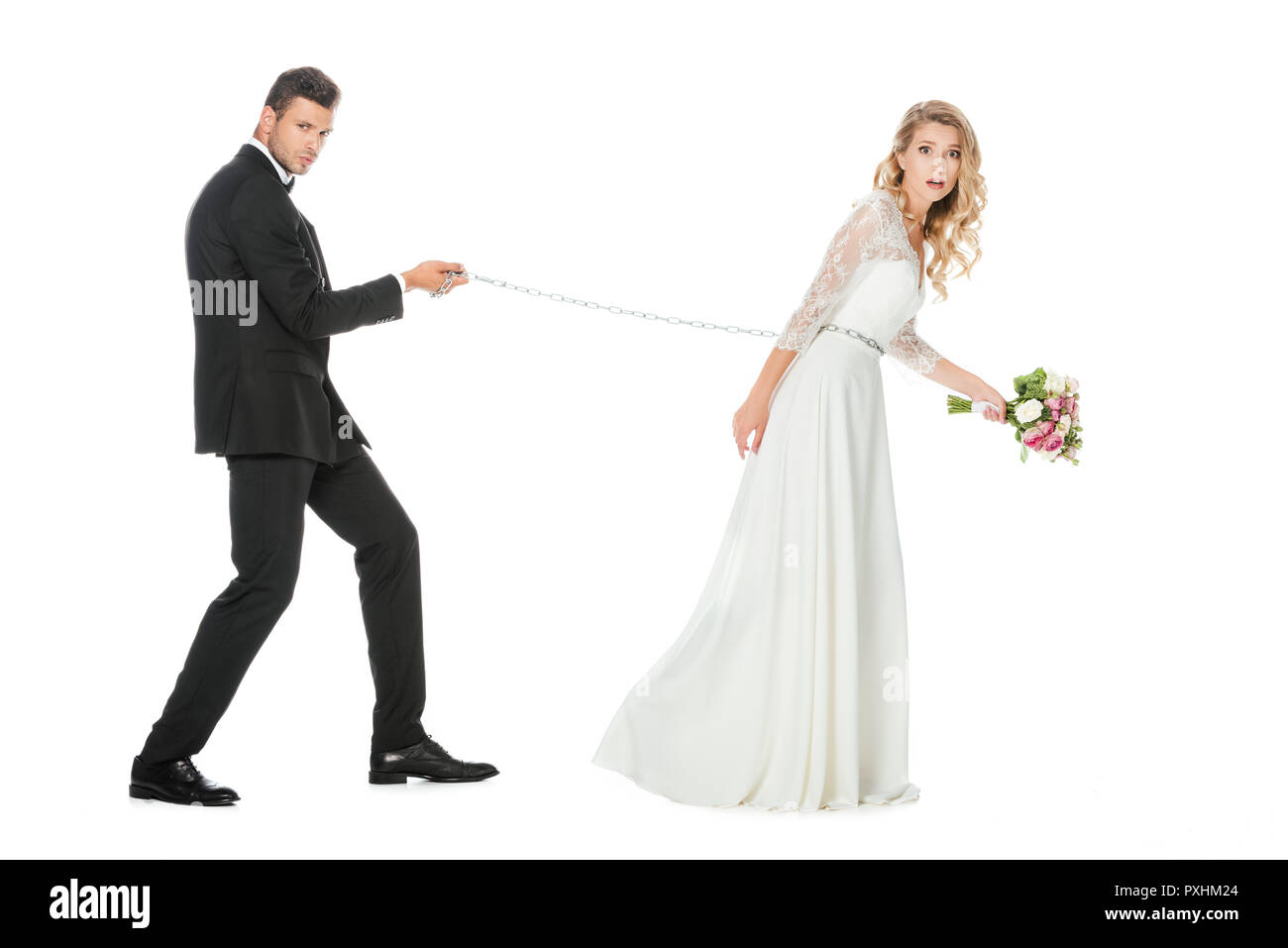 Seitenansicht der junge Bräutigam mit Kette und Leine schockiert Braut isoliert auf weißem Stockfoto