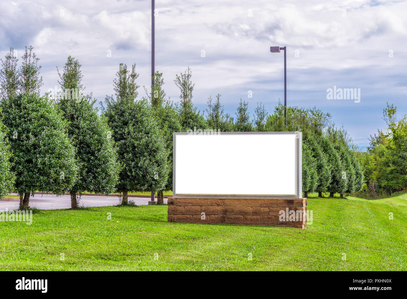 Horizontale Schuss ein leeres Zeichen, mit einem grünen baum laub Hintergrund unter einem bewölkten Himmel. Stockfoto