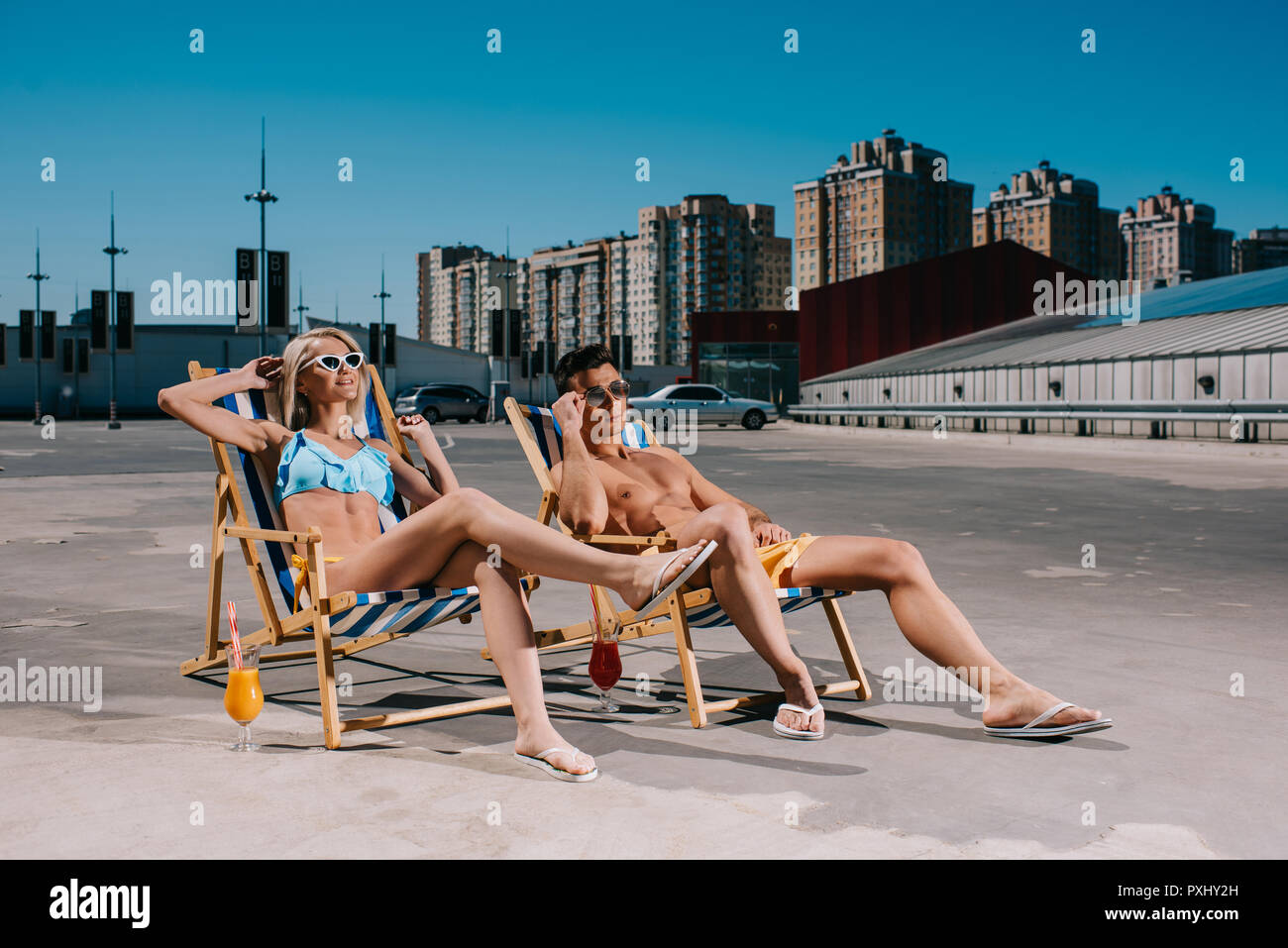 Junge attraktive Paar entspannende auf Liegestühlen entspannen auf Parkplatz Stockfoto