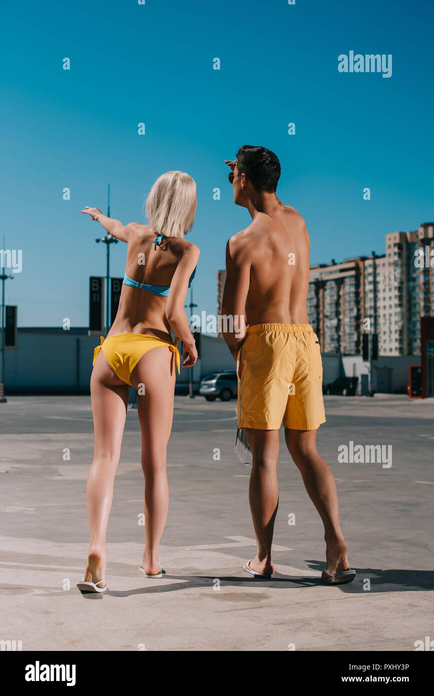 Ansicht der Rückseite des jungen Paares im Bikini und Badeshorts irgendwo hin auf Parkplatz Stockfoto