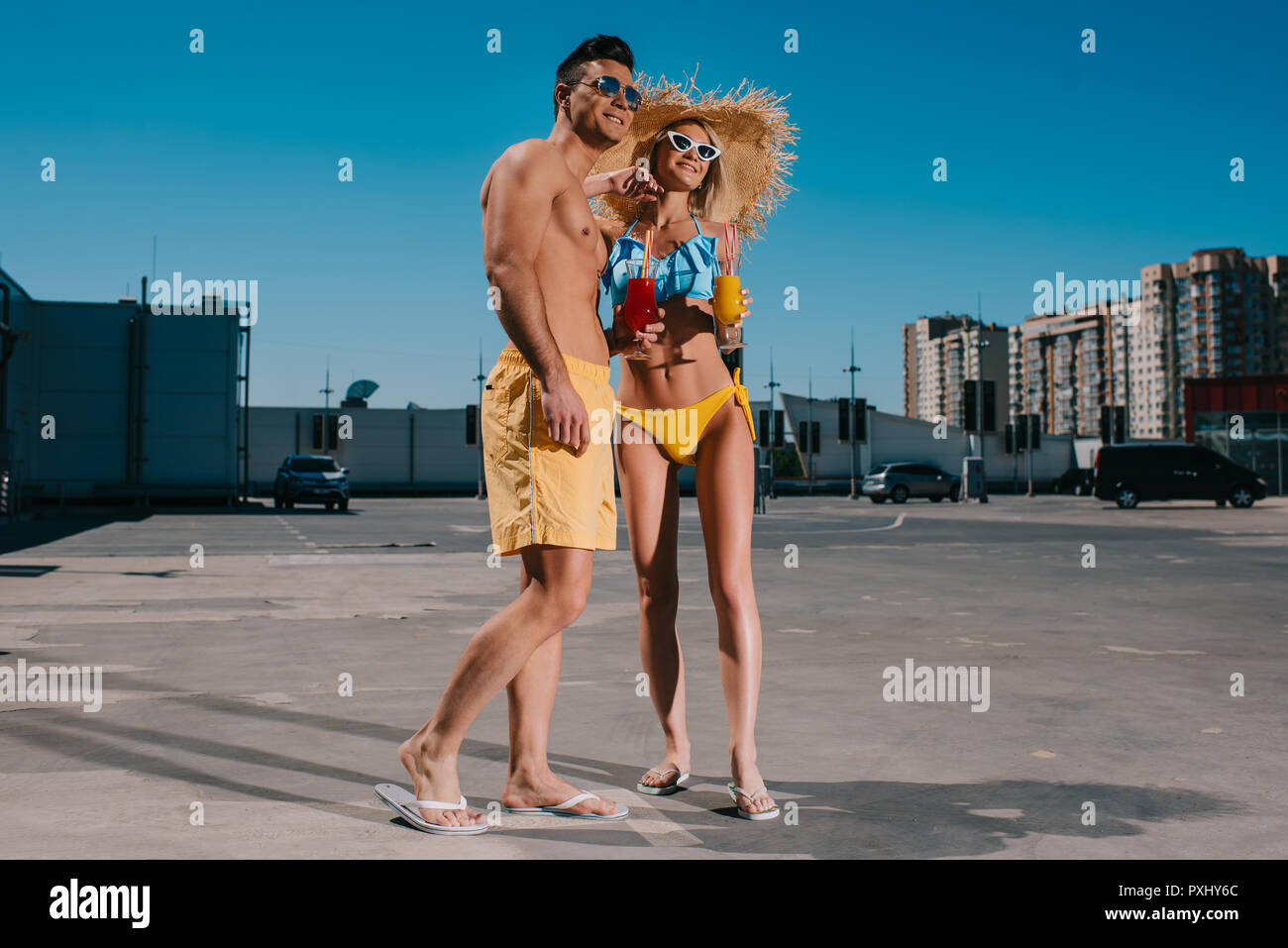 Junges Paar am Strand Kleidung mit erfrischenden Cocktails stehen auf Parkplatz Stockfoto