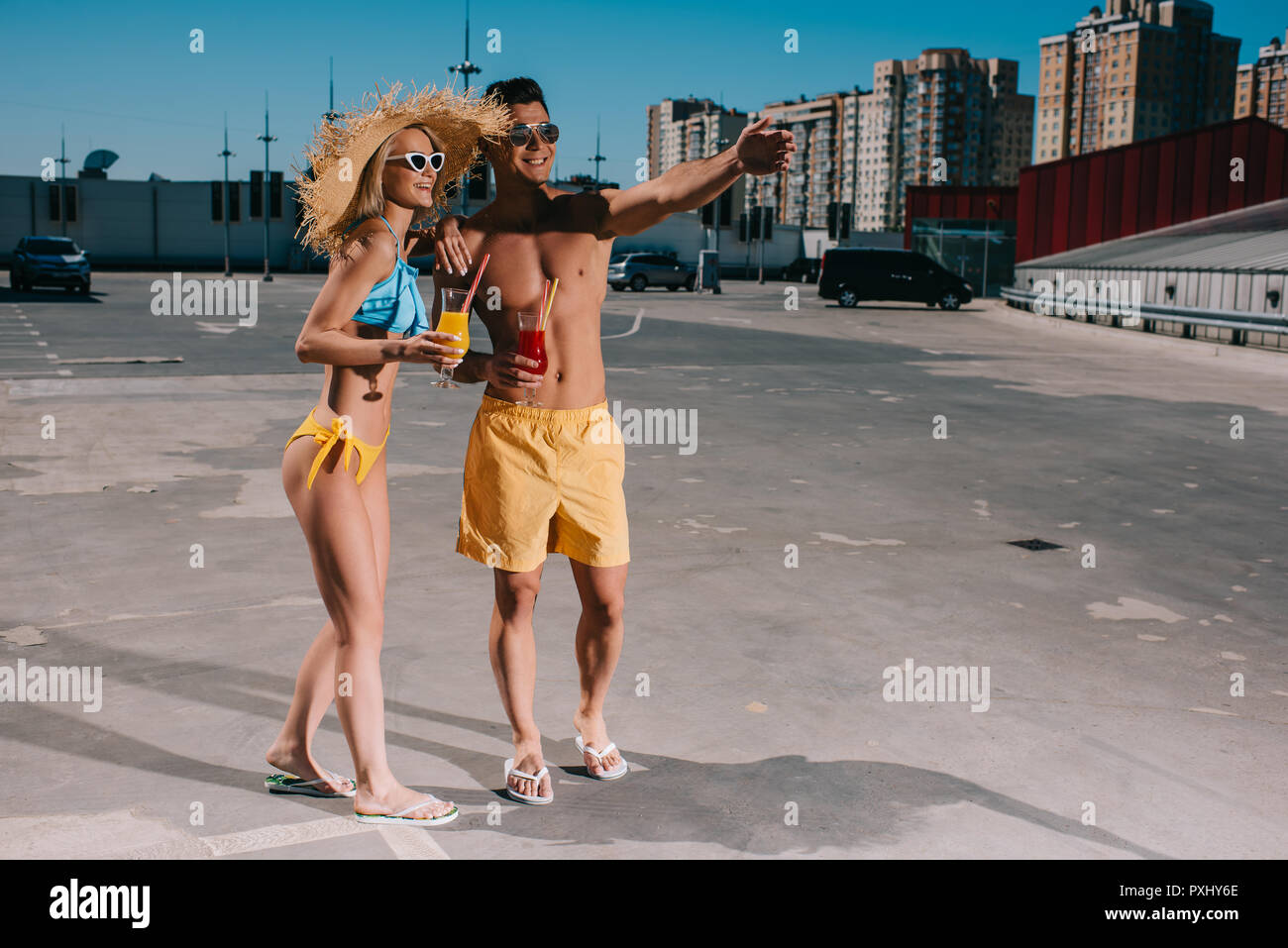 Glückliches Paar in Badebekleidung mit erfrischenden Cocktails stehen auf Parkplatz Stockfoto