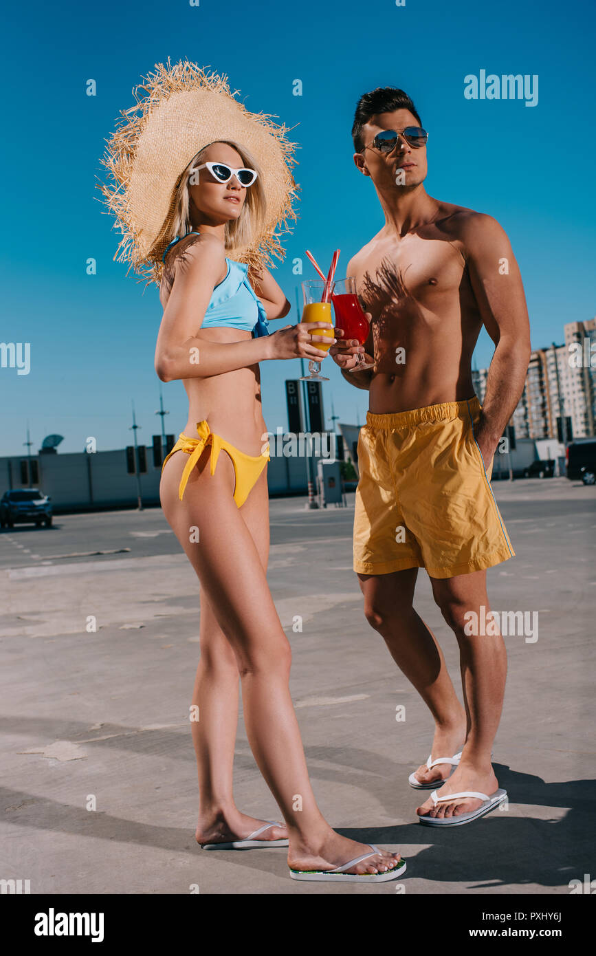 Attraktive junge Paar in Strand Kleidung mit erfrischenden Cocktails stehen auf Parkplatz Stockfoto