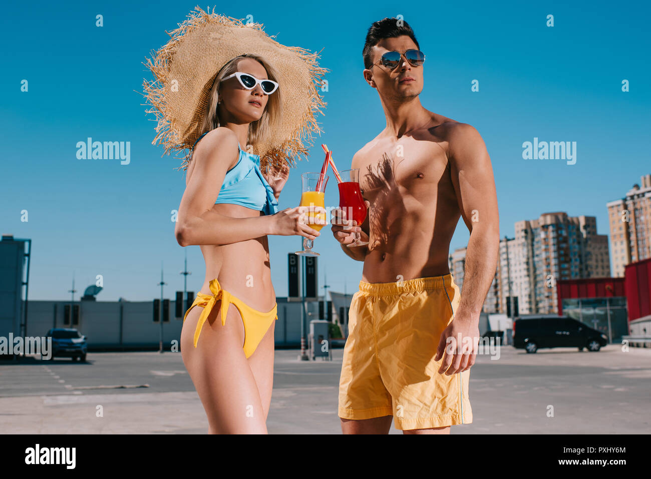 Schöne junge Paar in Strand Kleidung mit erfrischenden Cocktails stehen auf Parkplatz Stockfoto