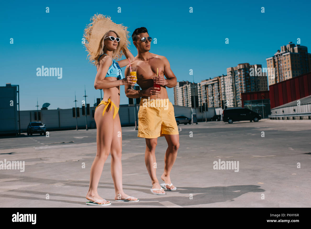 Glückliches junges Paar am Strand Kleidung mit erfrischenden Cocktails stehen auf Parkplatz Stockfoto