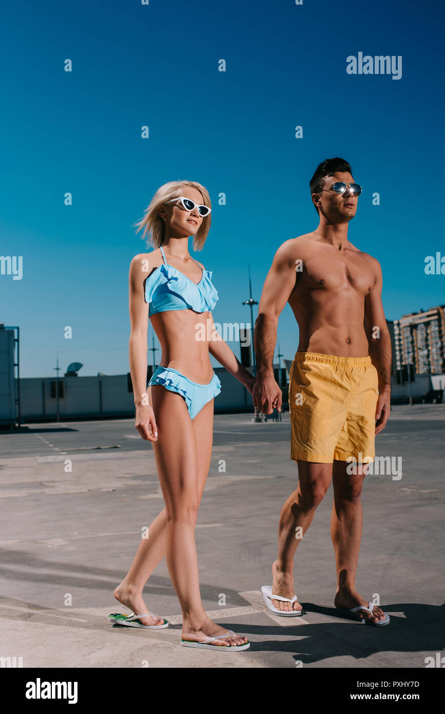 Junges Paar am Strand Kleidung halten sich an den Händen und laufen auf Parkplatz Stockfoto