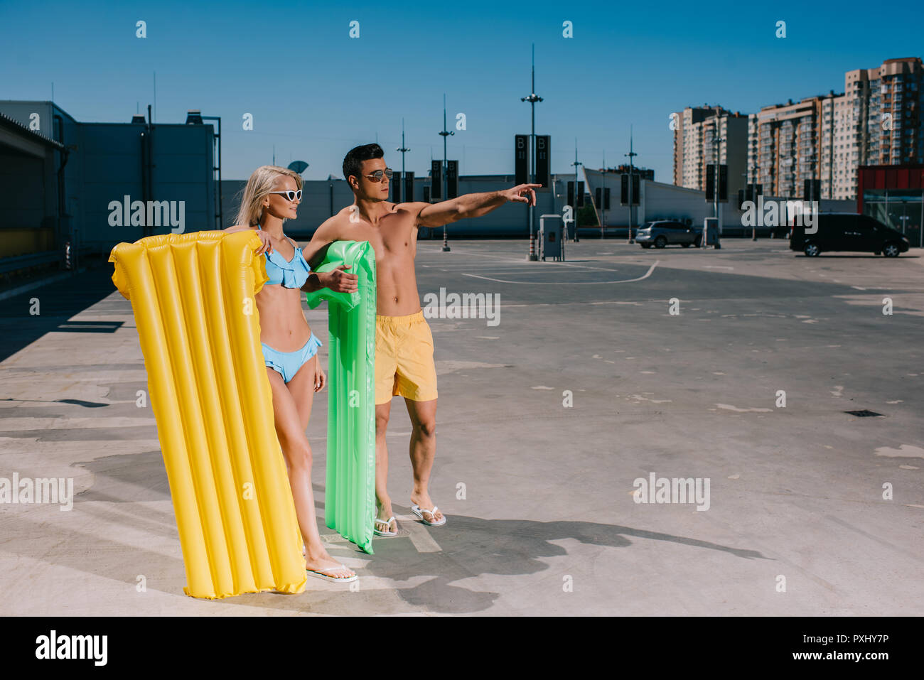 Glückliches junges Paar am Strand Kleidung mit aufblasbare Betten auf Parkplatz Stockfoto