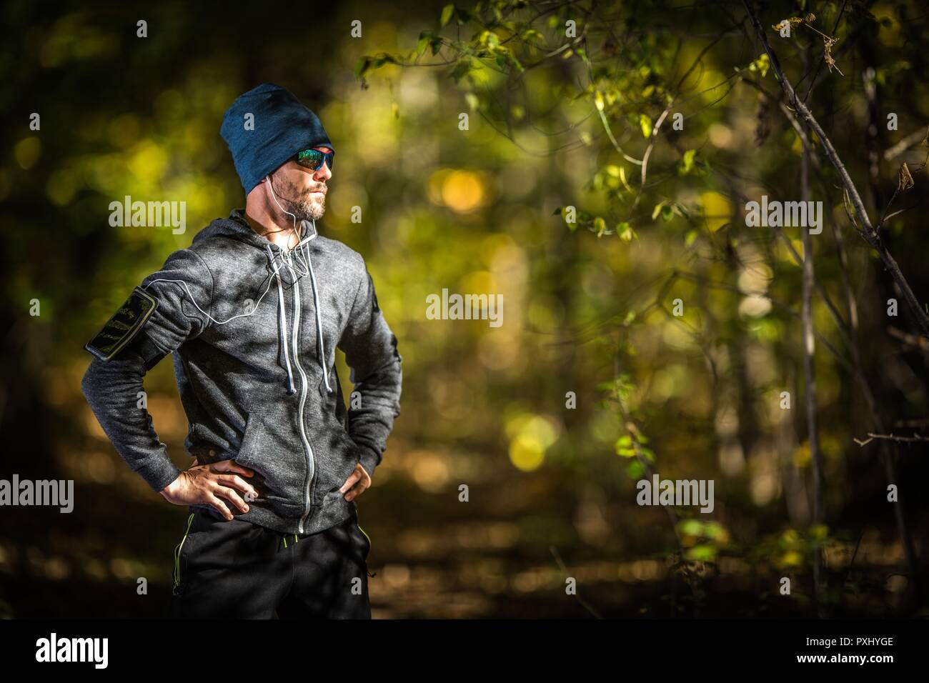 Kaukasischen Männern in seinem 30s mit Kopfhörer am späten Nachmittag Joggen im Wald. Outdoorsportler Runner. Stockfoto