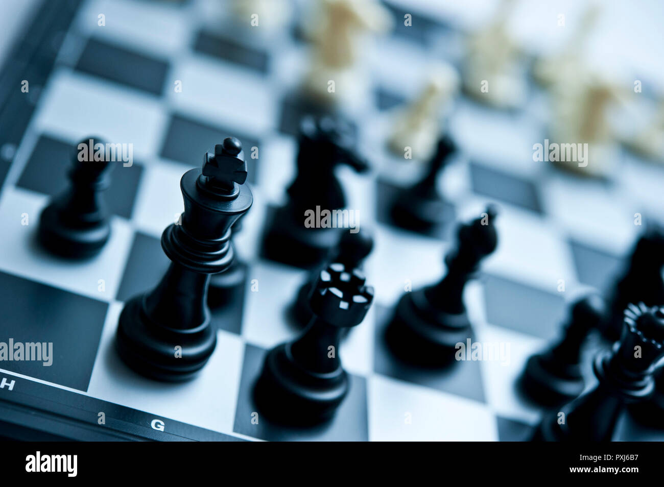 Nahaufnahme von schwarzen Schachfiguren auf einem schwarz-weißen Schachbrett mit selektiver Schärfe und geringer Schärfentiefe. Stockfoto