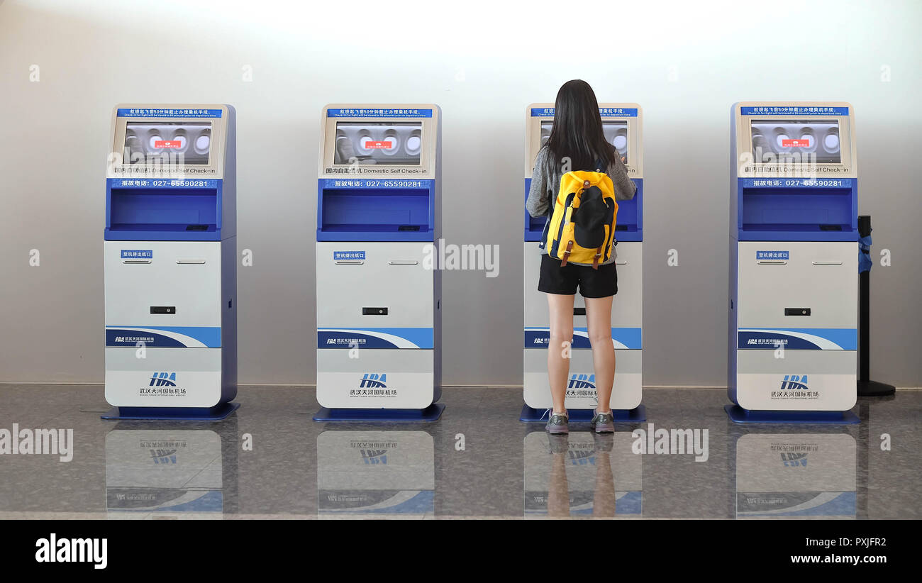 China Wuhan Tianhe - September 10, 2018: Die junge Frau mit dem Check-in-Automaten am Flughafen erhalten der Bordkarte. Stockfoto
