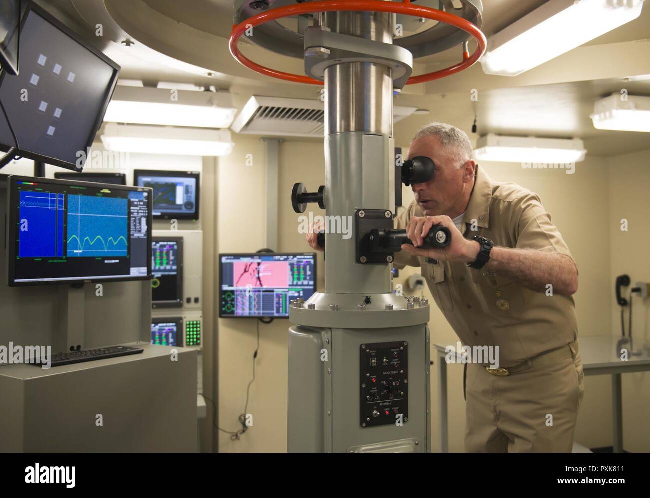 BANGOR, Washington (Juni 05, 2017) der hinteren Adm. John Tammen, Commander, U-Boot Gruppe 9, sieht aber das periskop im Angriff Zentrum von Trident Training Service Bangor neue U-Boot Brücke Trainer (SBT) nach der Ribbon Cutting. Der SBT gibt u-boot Brücke Teammitglieder zu navigieren, Pilot und Moor, das Boot zu und von einem Pier, während der Interaktion mit einem komplexen visuellen und akustischen Umwelt, mit allen relevanten Schiff Sensoren und Systeme. Stockfoto