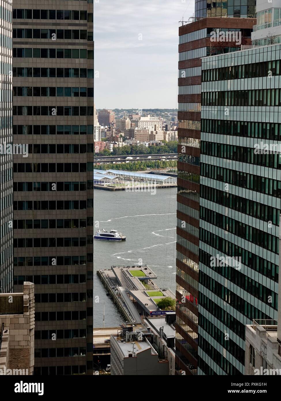 Fähre gesehen kommen in den Hafen, zwischen hohen Wolkenkratzern, vorbei an Pier 15 auf den East River, Lower Manhattan, New York, NY, USA. Stockfoto