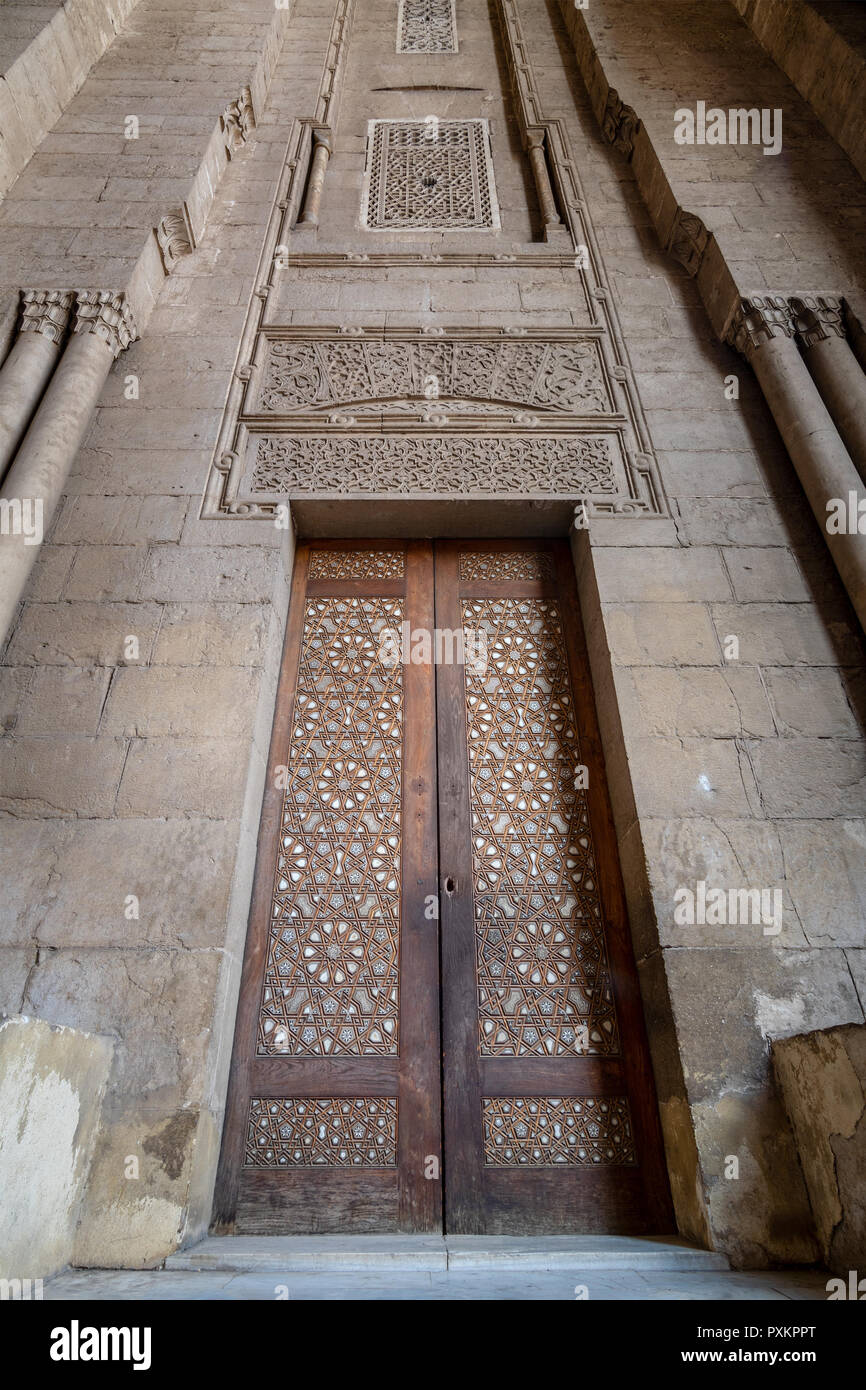 Externe Stil der alten Steine Steinwand mit Arabesque dekoriert Holztür von Stein gerahmt verzierten zylindrische Lichtmasten, die zu Al Rifai Moschee, O Stockfoto
