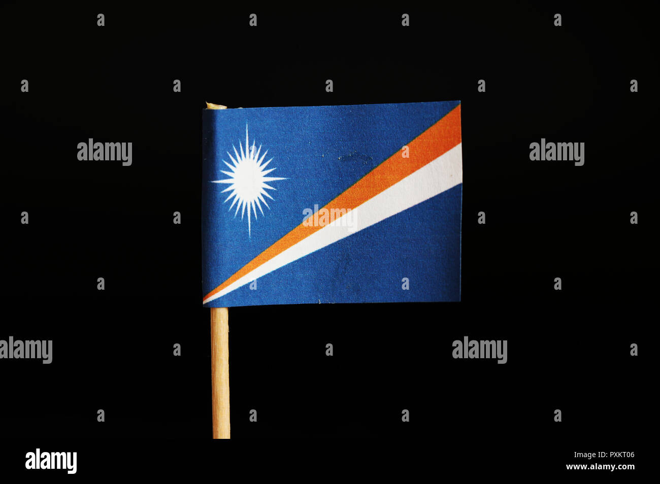Eine offizielle Flagge der Marshall Inseln auf Holzstab auf schwarzem Hintergrund. Marshall Inseln im Pazifischen Ozean und gehört zu Ozeanien. Sonne auf Stockfoto