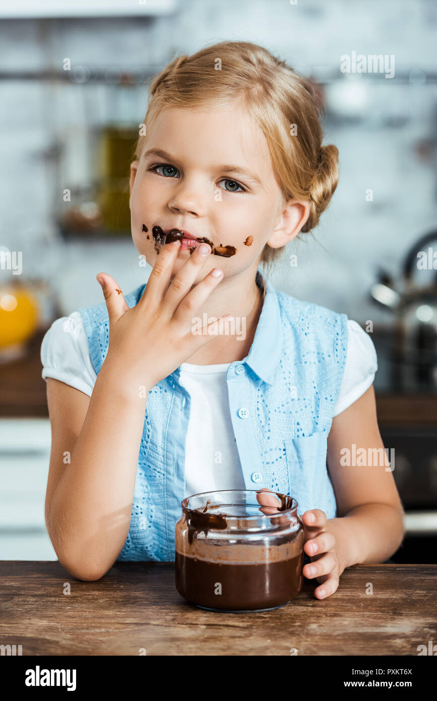 Süßes kleines Kind essen leckere Schokolade verteilt und Kamera Stockfoto