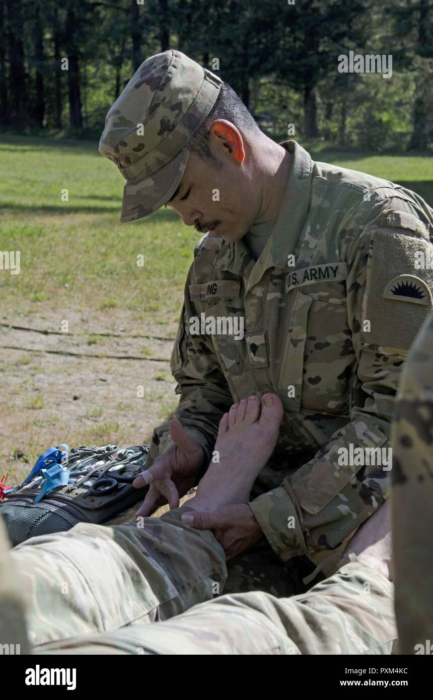 Oklahoma Army National Guard SPC. Thomas König, ein Medic zu Unternehmen, 1 Battalion, 186Th Infantry Regiment, 41st Infantry Brigade Combat Team zugewiesen ist, stellt die erste Überprüfung auf Verletzung eines Soldaten während der Air Assault Kurs am Lager Rilea in Warrenton, Virginia, 6. Juni 2017 statt. King's geholfen hat der Soldat im Air Assault praktische Übungen fort, nach Auslösung in einem Loch und Verstauchungen seinen Knöchel. Der König war ein Teil des medizinischen Teams, die die Air Assault und Pathfinder Kurse. Stockfoto