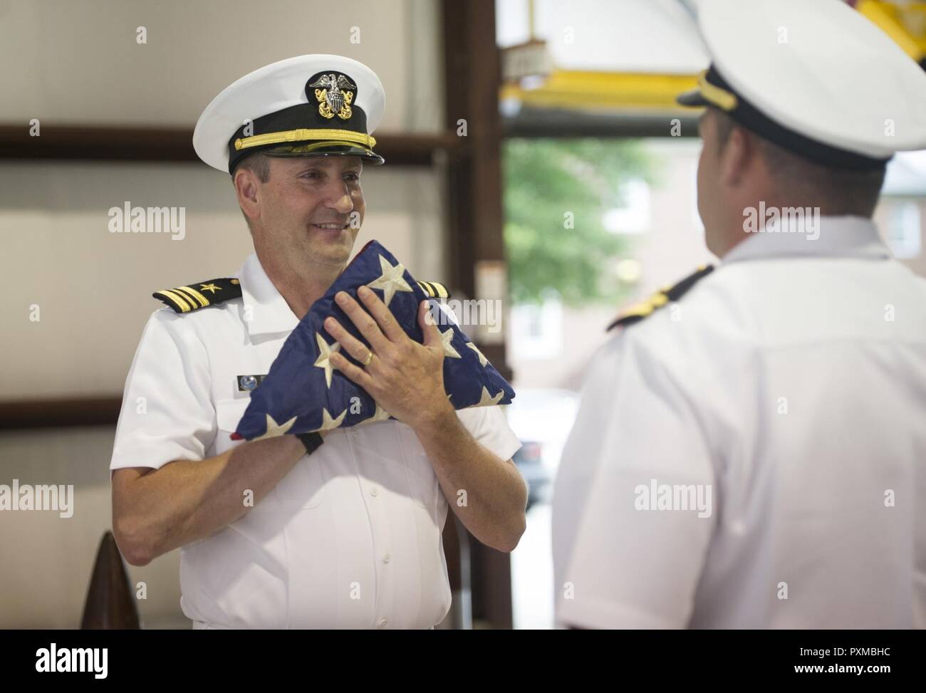 NORFOLK (8. Juni 2017) Lt.Cmdr. Gregory Curl begrüßt mit einer Flagge in seinem Ruhestand Feierstunde im Zentrum für Naval Aviation Technical Training Unit auf der Naval Station Norfolk. Curl letzte diente als der Flugzeugabfertigung Offizier an Bord der Flugzeugträger USS George Washington (CVN 73). Stockfoto