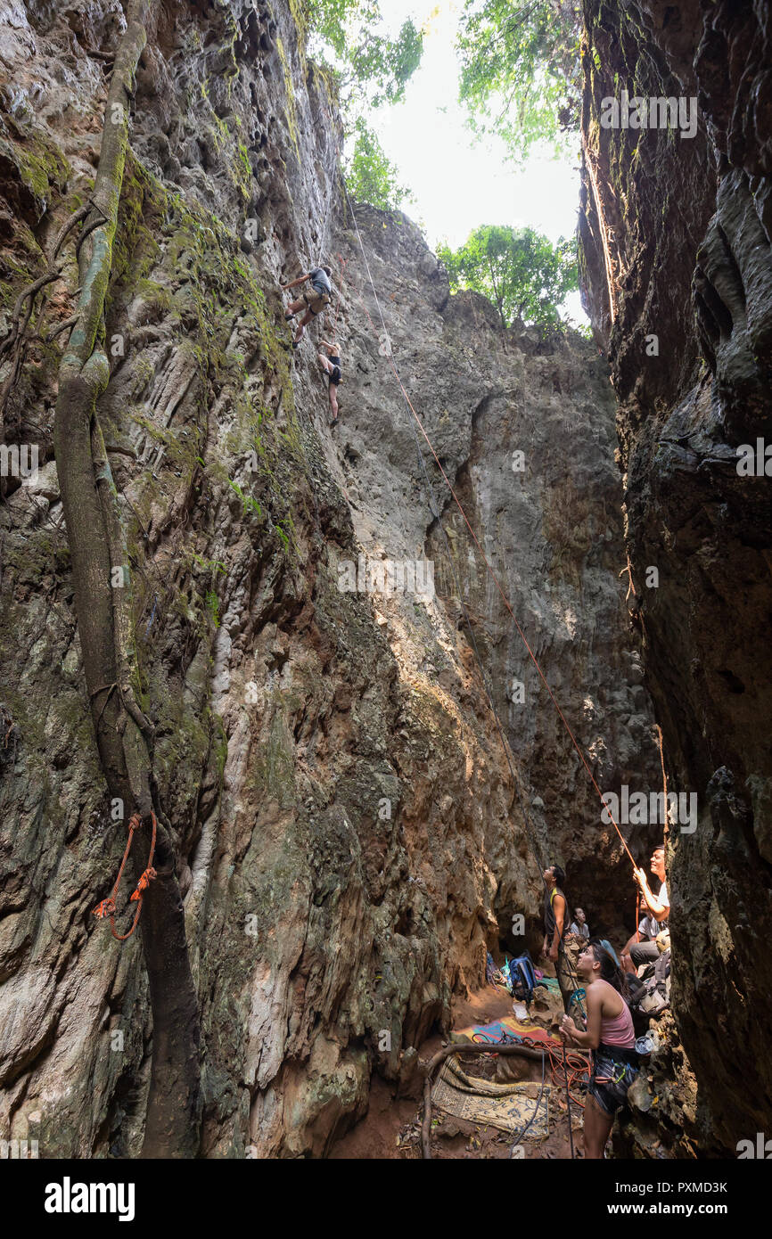Top Gruppe von Touristen Seil klettern und in einer engen Schlucht mit zwei steilen und hohen Kalkstein Gesichtern, das ist ein beliebter Klettern Website in Vang Vieng Stockfoto
