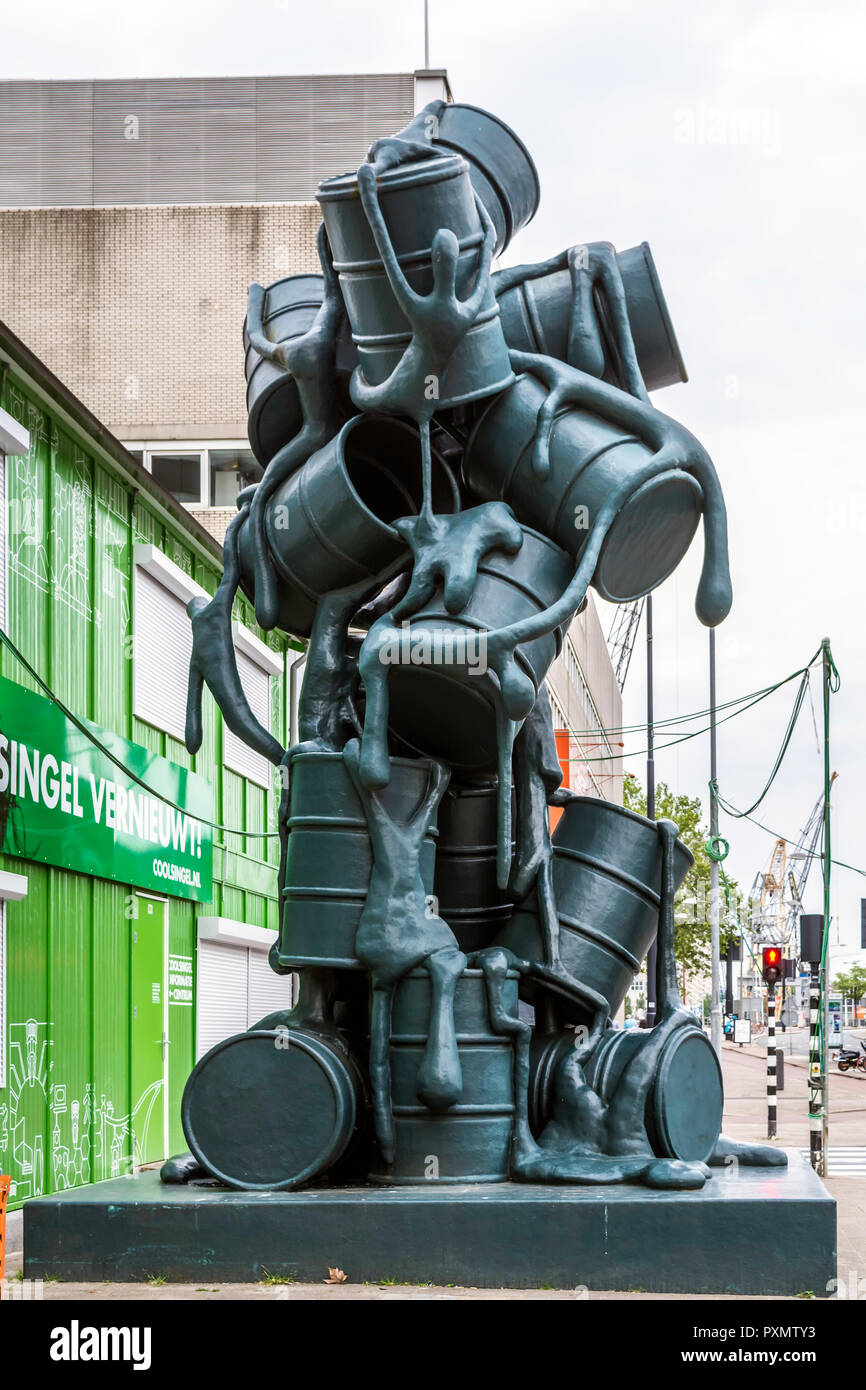 Acht Meter hohe Schwarze Skulptur mit lebensgroßen Ölfässer tropfende sirupartige Masse, die Formen menschlichen Figuren. Stockfoto