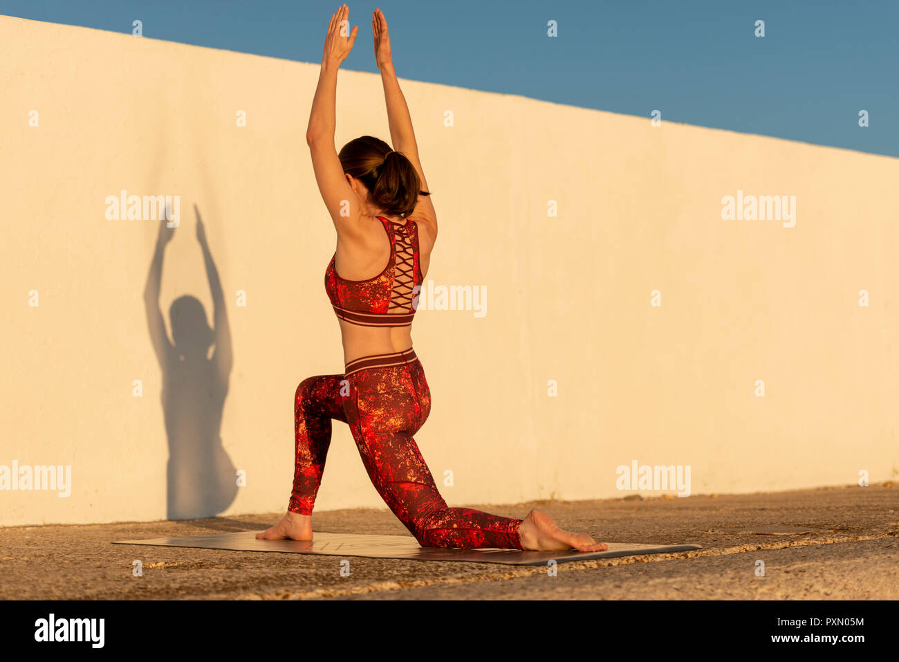 Frau Yoga auf einer Matte draußen in der Sonne Stockfoto