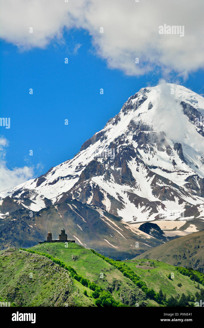 Mount Kazbek (5047 m), den höchsten Gipfel in Georgien, an der Grenze zu Russland, mit dem gergeti Trinity Church an seinen Hängen. Khevi-Kazbegi Region. Georgien, Kaukasus Stockfoto