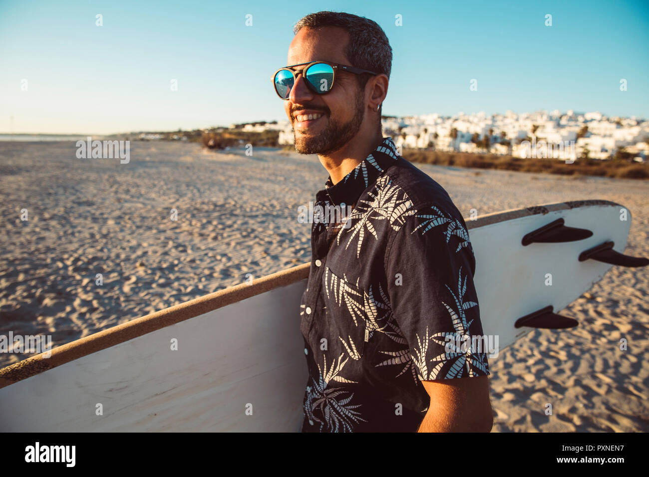 Mann am Strand Surfbrett Durchführung Stockfoto