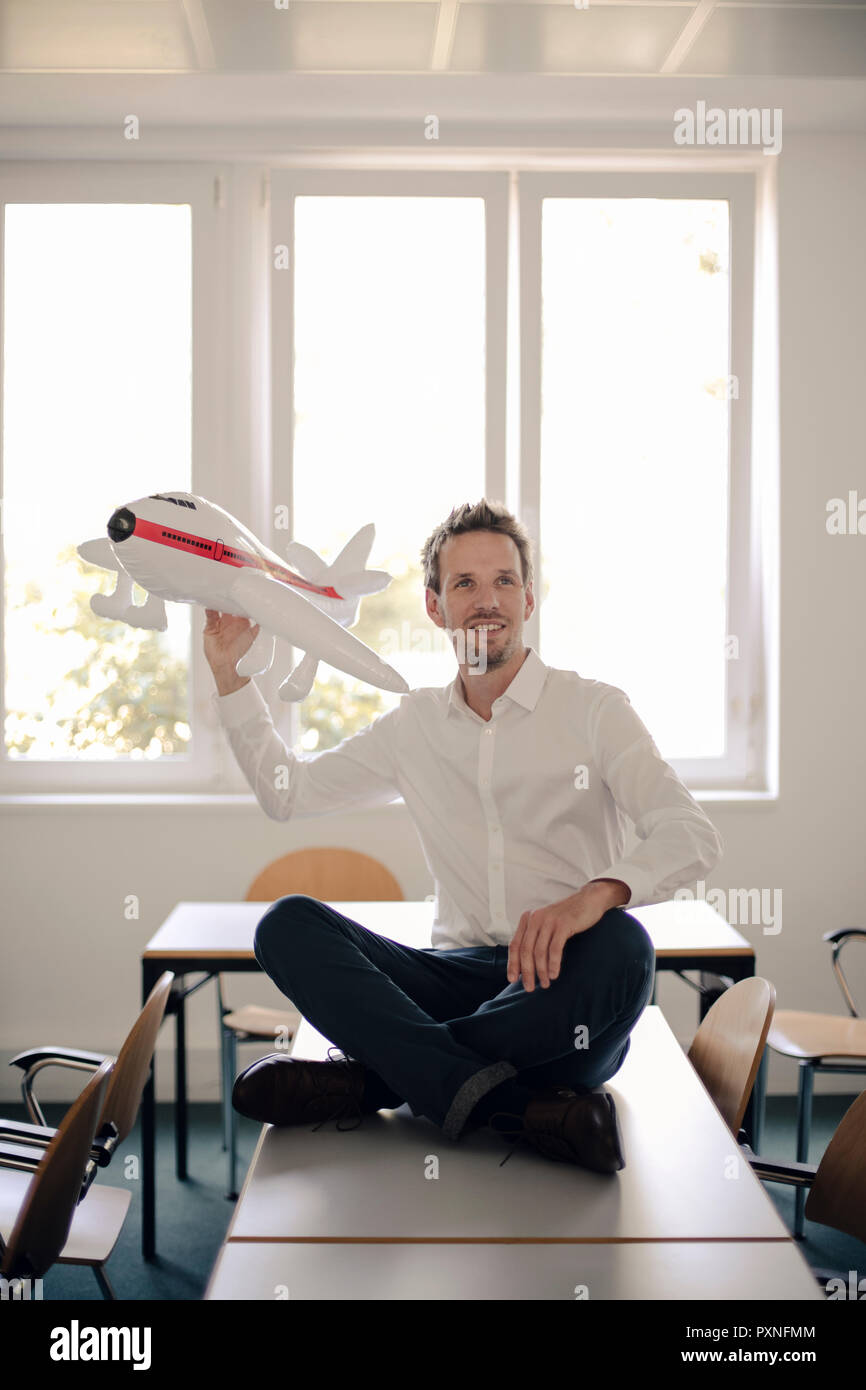 Geschäftsmann spielen mit aufblasbaren Flugzeug im Büro Stockfoto