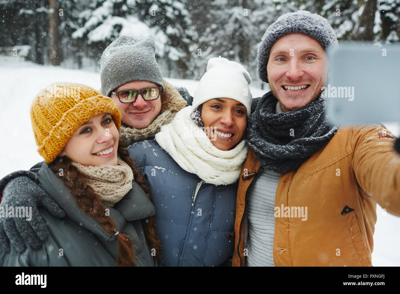 Positiv Begeistert junge Freunde in warmen Mützen und Schals posieren für selfie und umarmt in Winter Park Stockfoto