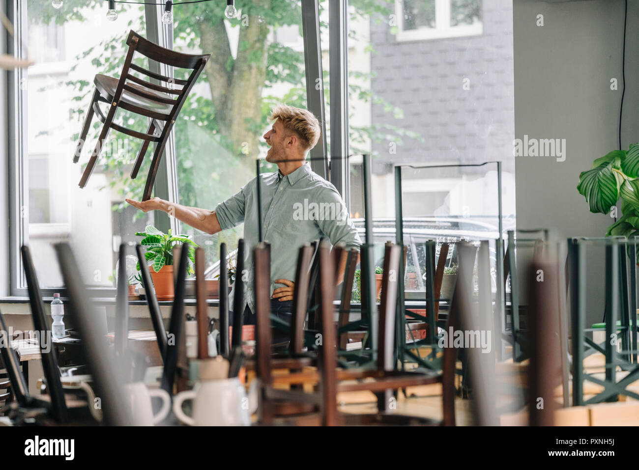 Mann balancing Stuhl auf seine Hand, seine Coffee shop schließen Stockfoto
